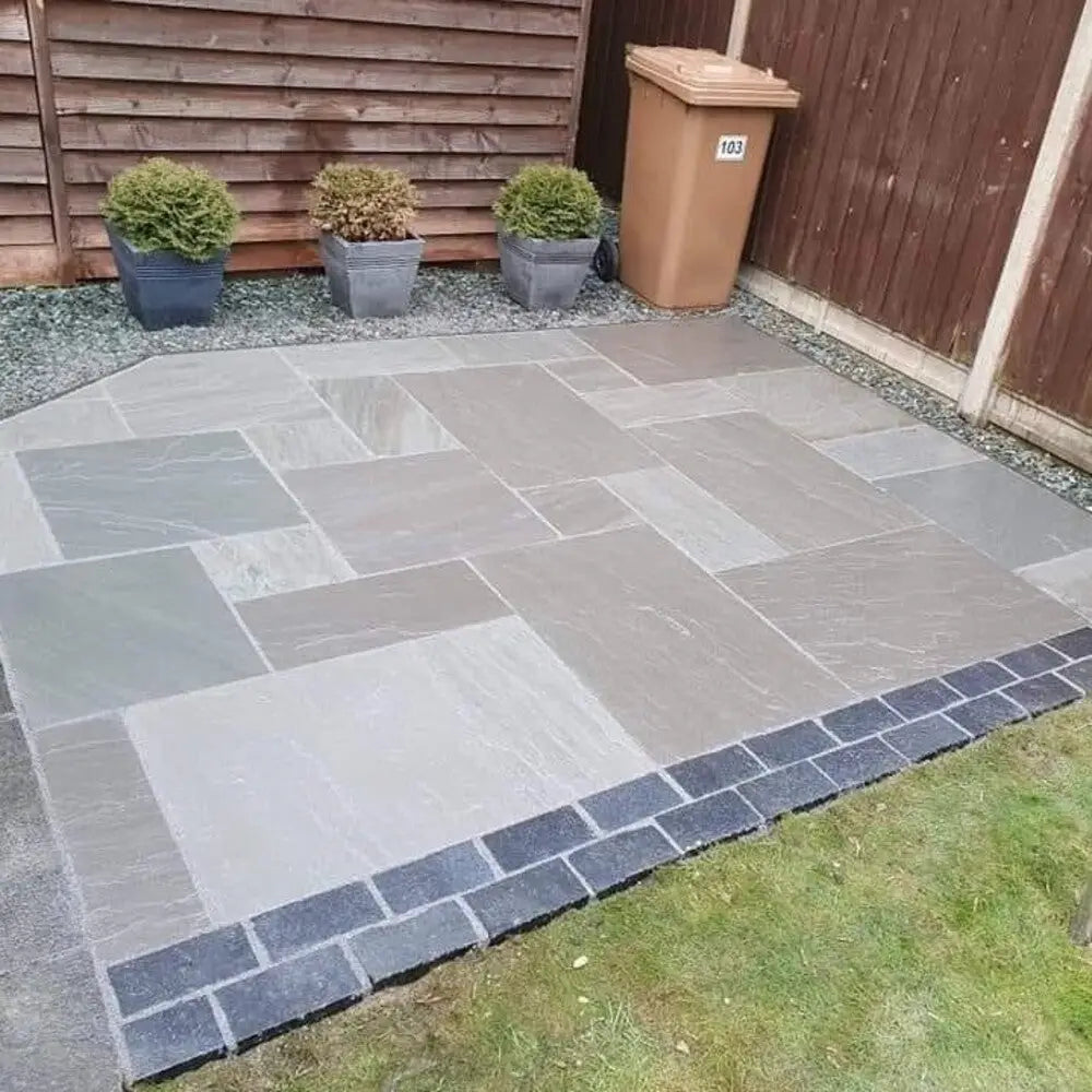 Back garden patio outlined with black limestone cobbles.