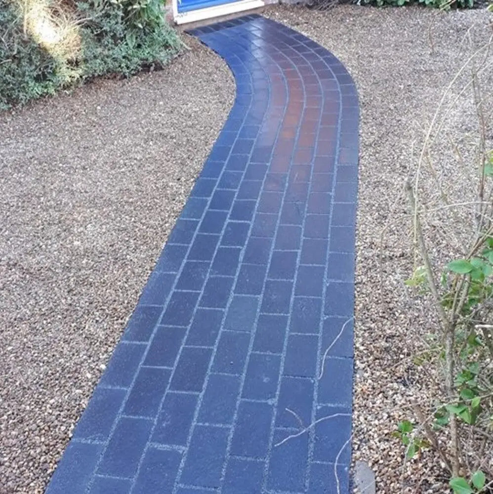 A path made of black limestone cobbles, textured and regular.
