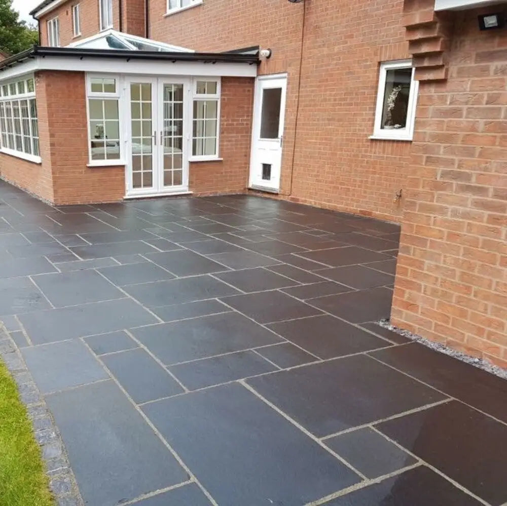 Mixed size black limestone paving slabs in an outdoor patio.