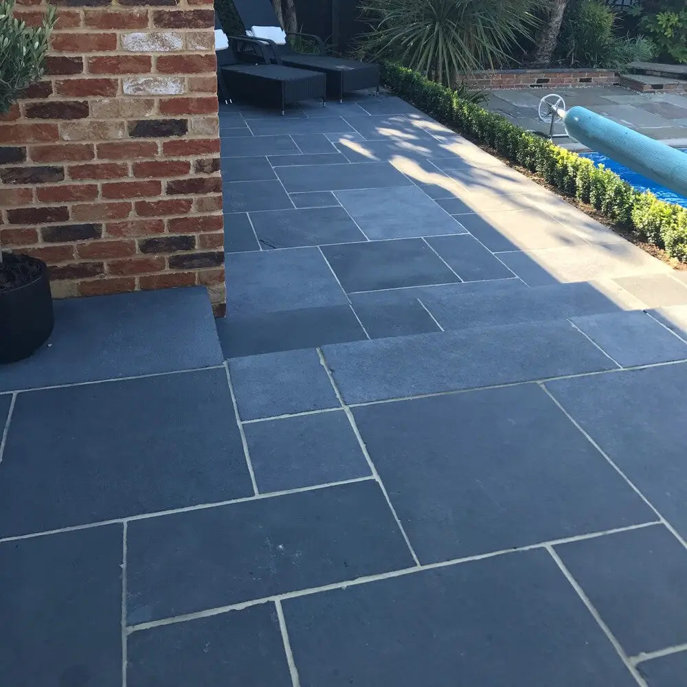 Black limestone paving slabs in various sizes forming a backyard patio.